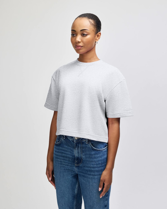 A grey mid-length boxy top with short sleeves, featuring a side view of a model with long braids.