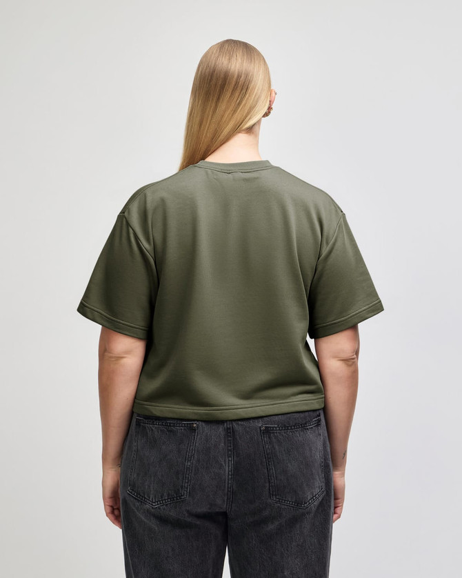 A mid-length boxy top in olive green, featuring short sleeves and a relaxed fit, with a logo present.