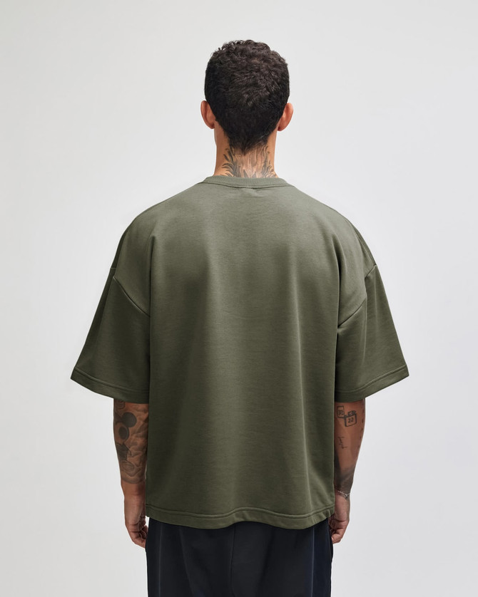 A unisex oversized boxy top in olive green, featuring a simple design and a logo on the back.