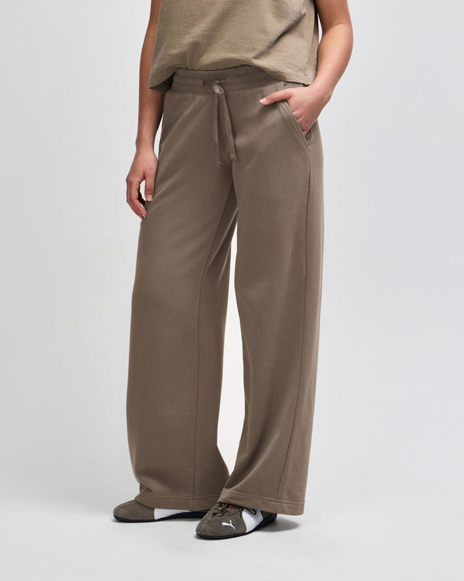 Wide leg pants in brown French terry fabric. Features a drawstring waist and side pockets. Appears on a mannequin.