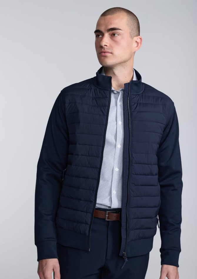 A navy blue men's jacket with a quilted front silhouette, paired with a collared shirt underneath.