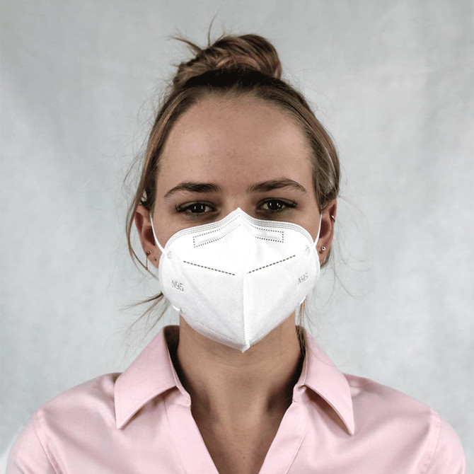 A white N95 respirator face mask worn by a person, featuring a logo and a plain background.