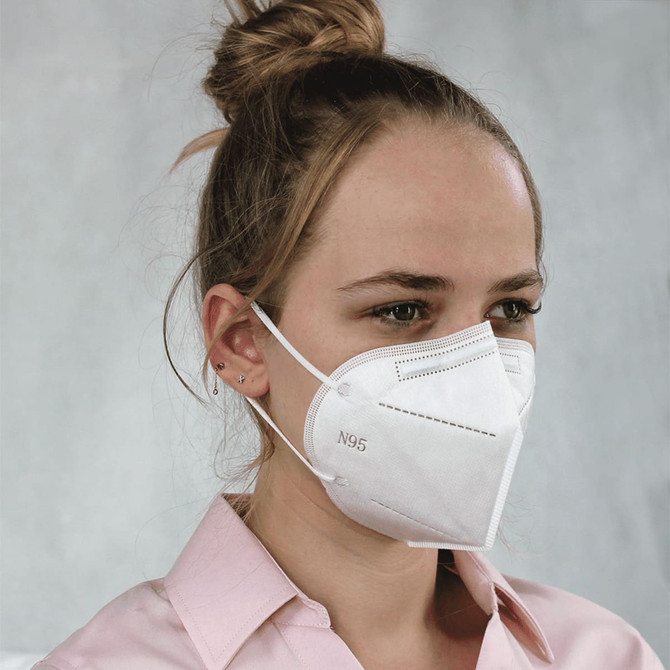 A white N95 respirator face mask being worn by a person with long hair, featuring a logo on the side.