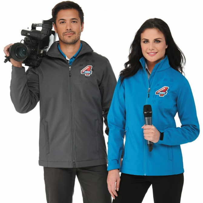 A grey softshell jacket worn by a man holding a camera, and a blue softshell jacket worn by a woman with a microphone.