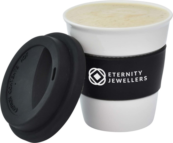 A ceramic coffee mug in white with a black silicone sleeve and lid, featuring a logo.