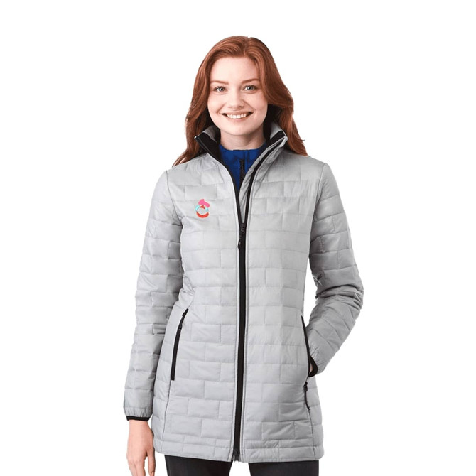 A woman wearing a lightweight, packable insulated puffer jacket in light grey with a logo on the chest.