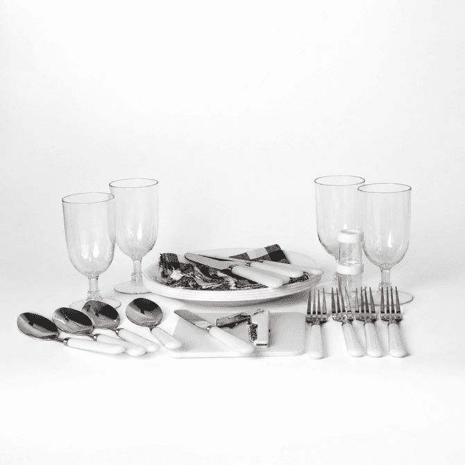 A picnic set features white-handled cutlery, glass tumblers, and serving platters on a white background.