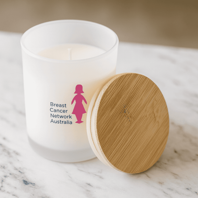 A medium white candle with a bamboo lid and a logo on the frosted glass, set on a marble surface.