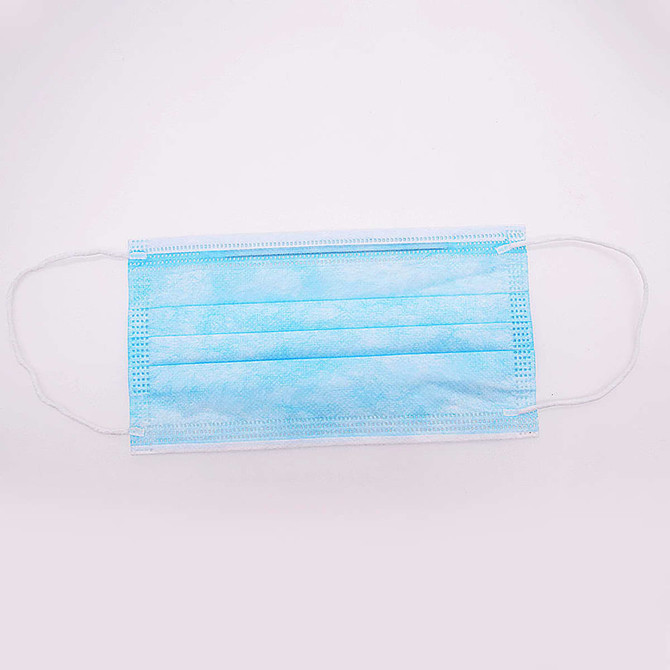A triple layered cloth face mask in light blue, featuring ear loops and a pleated design, with a logo present.