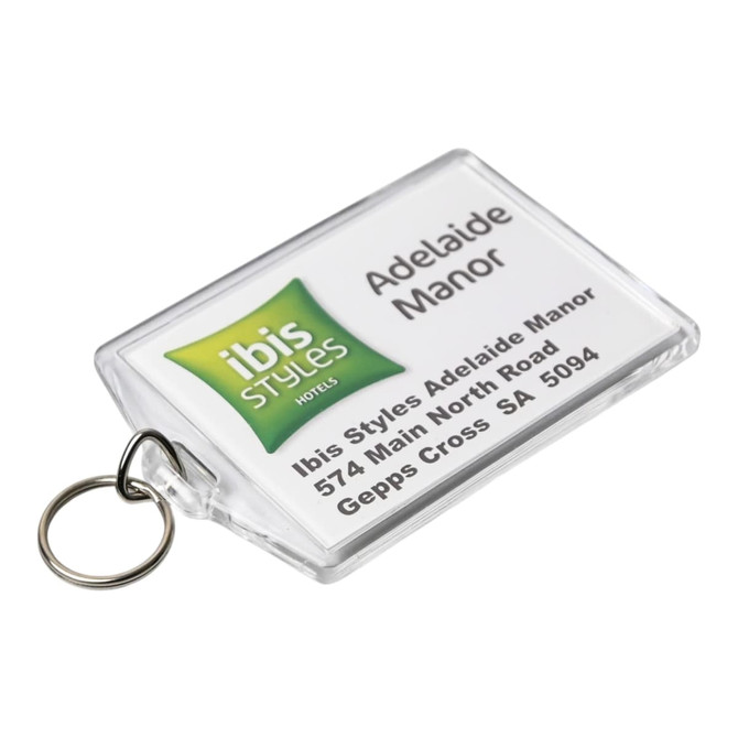 A clear hotel keychain featuring a logo and details for Ibis Styles Adelaide Manor, attached to a metal ring.