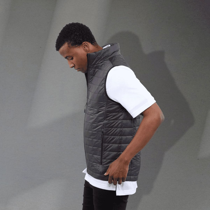 A men's lightweight packable insulated puffer vest in black, worn over a white shirt, featuring a logo.