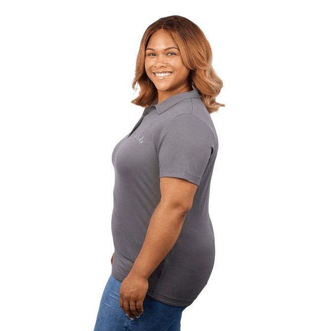 A grey women's polo shirt with a fitted design, featuring a logo on the chest, displayed on a model.