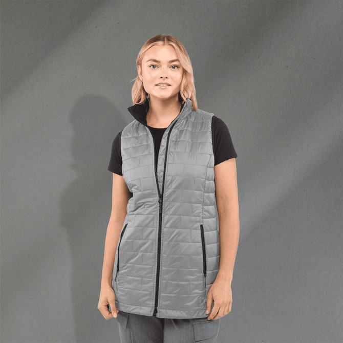 A lightweight, packable insulated puffer vest in grey, featuring a zip front and side pockets, worn over a black shirt.