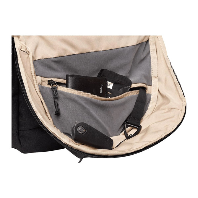 An open black backpack interior featuring a grey lining, small pockets, and various items like a wallet and a keychain.