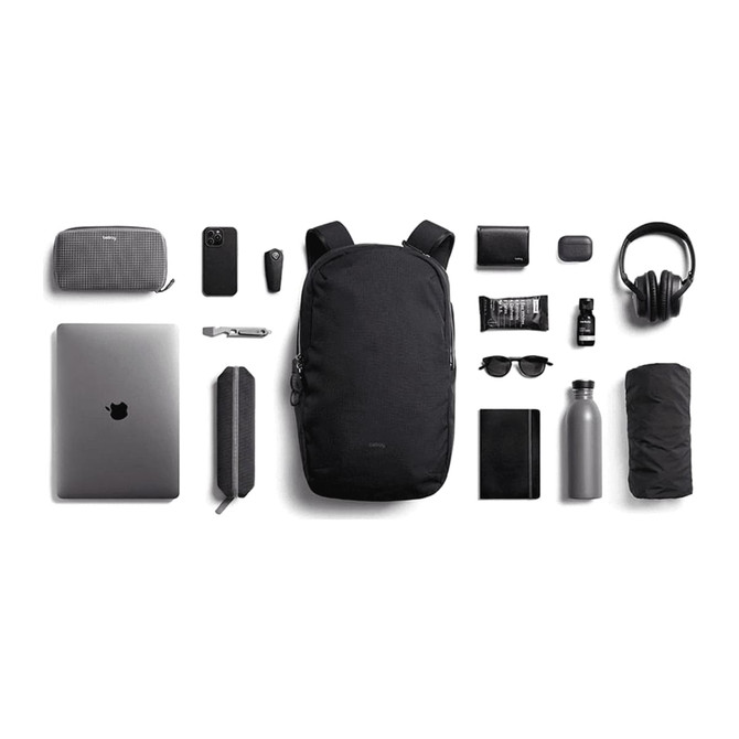 A black Bellroy Via Backpack 20L surrounded by a laptop, drink bottle, sunglasses, and various accessories.