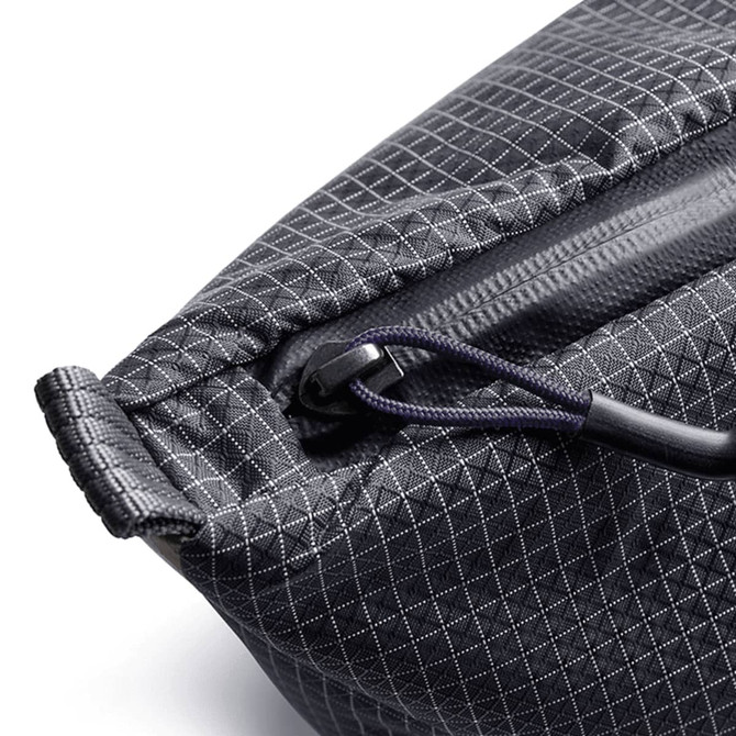 A close-up of a black, textured cooler bag featuring a zipper and a handle. It has a subtle diamond pattern.