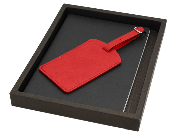 A red luggage tag and a notebook set in a black presentation box. The box has a plain exterior with no branding.