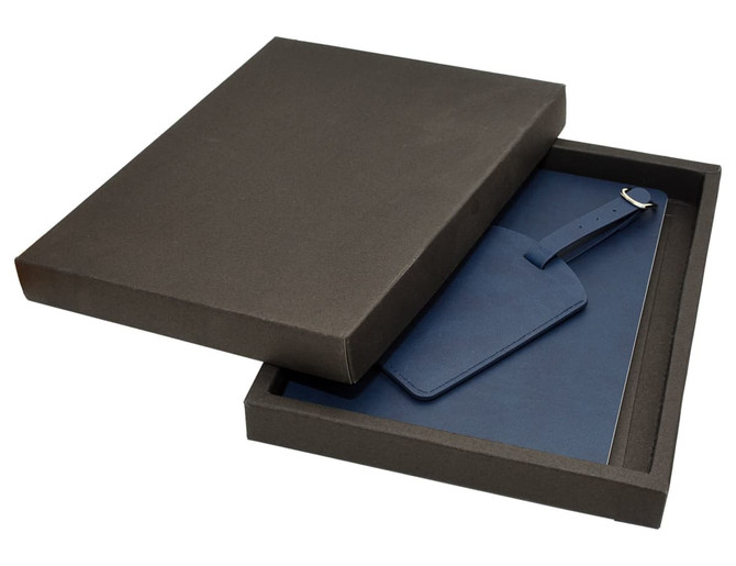 A dark box containing a blue travel journal and matching luggage tag. The items are neatly presented inside the box.