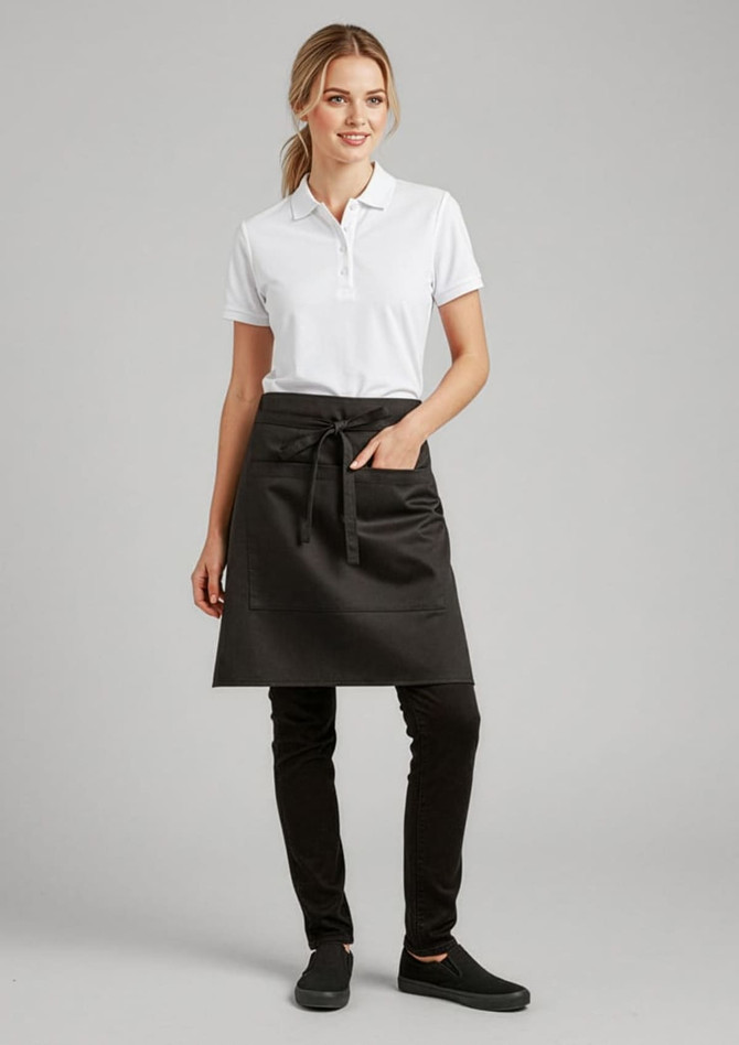 A woman wearing a black short waisted apron over a white polo shirt, paired with black pants and shoes.