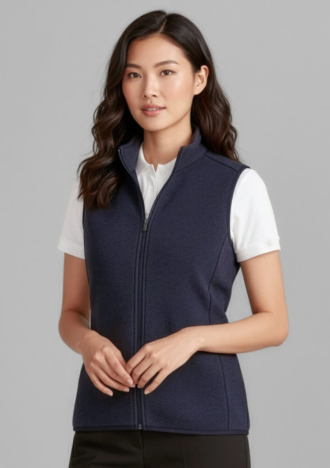 A woman wearing a navy zip-front vest over a white shirt, featuring a zipped front and a standing collar.