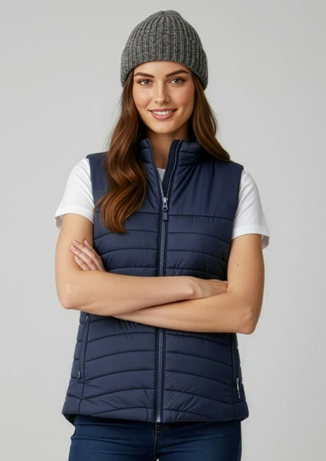 A navy women's expedition vest featuring a zip front and a grey knitted beanie. The model is smiling with arms crossed.