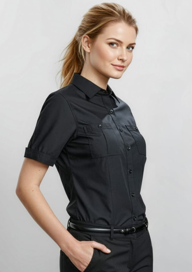 A black short sleeve button-up shirt with a sleek design and two chest pockets, worn by a model.