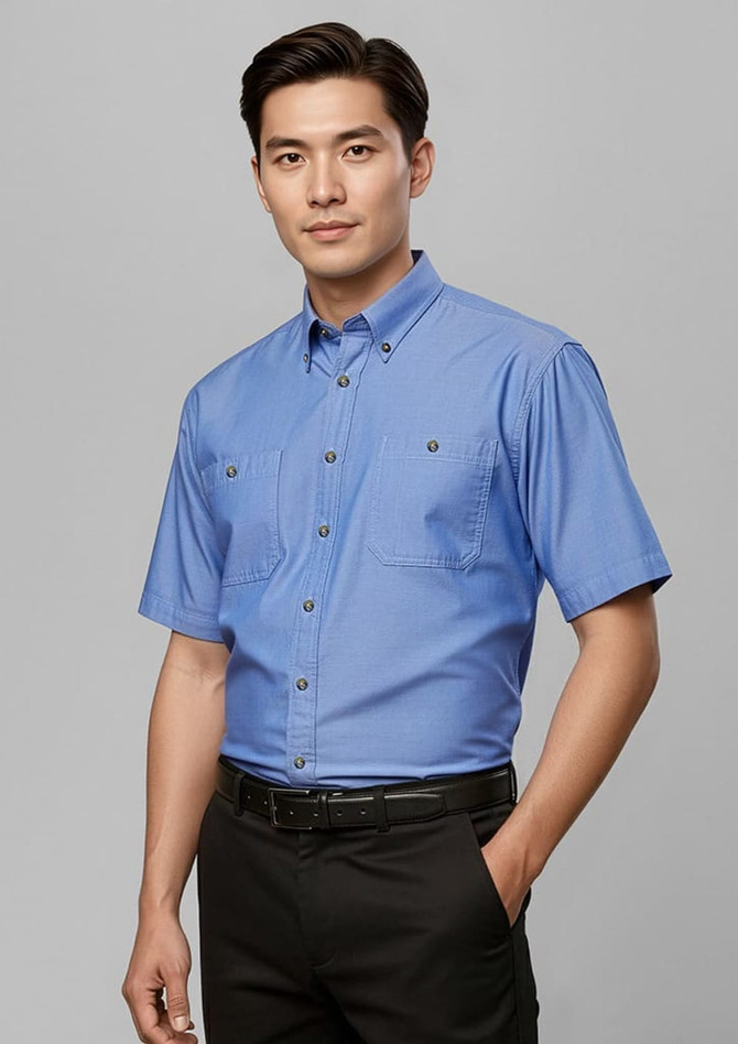 A short-sleeve button-up shirt in light blue, featuring a collar and two front pockets, with a logo on the fabric.