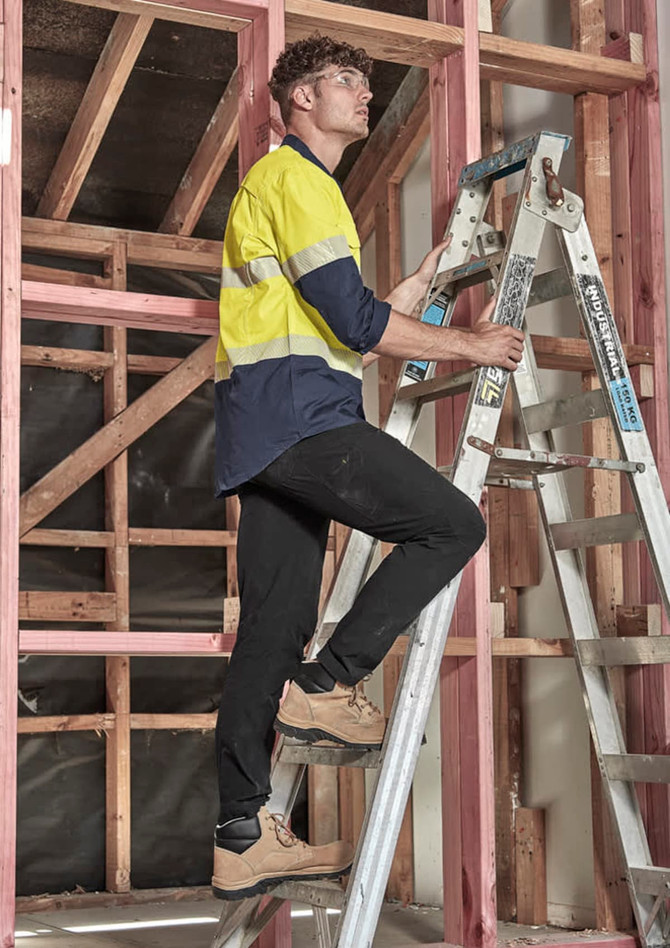 Lightweight black cargo pants worn by a man climbing a ladder in a building under construction.