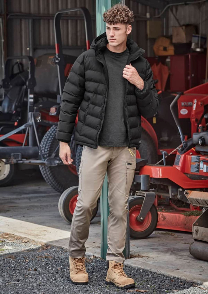Men's essential basic stretch cargo pants in beige, paired with a black puffer jacket and tan boots, set in an outdoor environment.