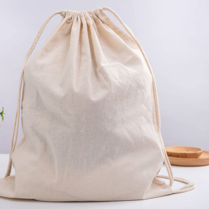 A beige drawstring bag made of fabric, featuring two cord straps, displayed against a plain background.