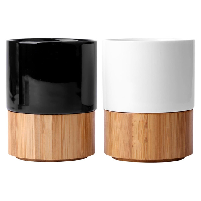 A pair of ceramic mugs featuring a black and a white glossy finish, both with bamboo bases. Each has a branding logo.