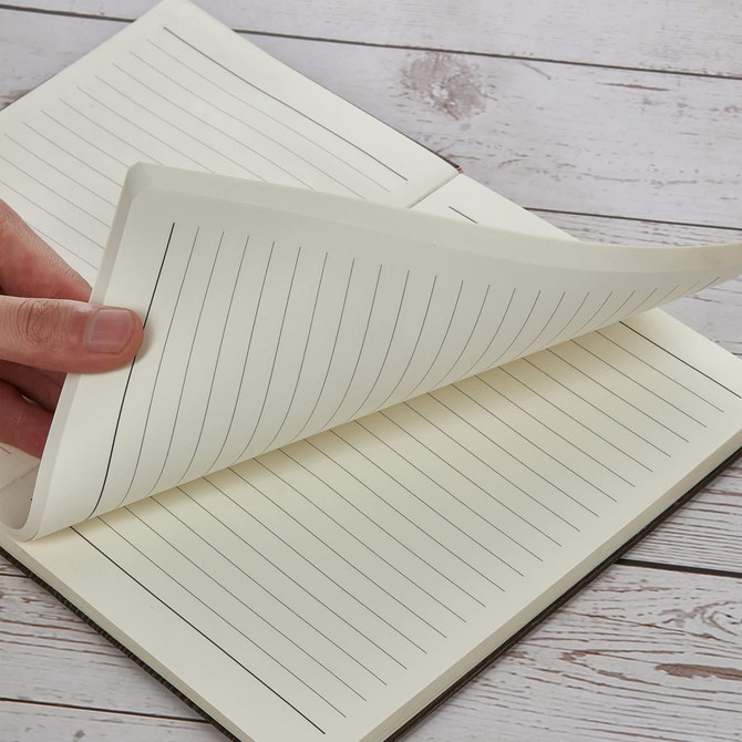 A5 wood-look notebook with lined pages, featuring a hand turning the pages, set on a wooden surface.