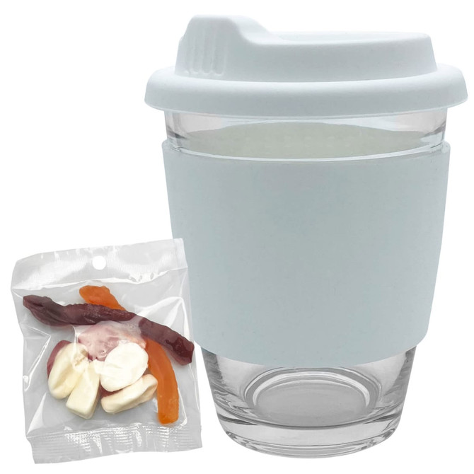 A reusable coffee cup in clear glass with a light blue silicone sleeve, accompanied by a pack of jelly candies.