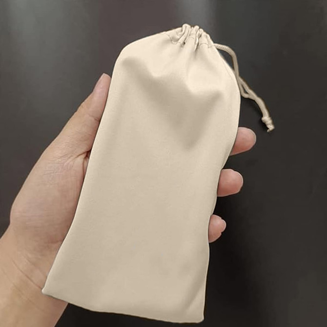A beige cotton drawstring pouch held in a hand, featuring a cinched top and smooth texture.