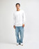 A model wearing a white heavyweight cotton unisex long sleeve T-shirt paired with blue jeans and white shoes.