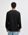 A black heavyweight cotton unisex long sleeve t-shirt viewed from the back, worn with olive green pants.