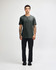 A man stands wearing a dark grey unisex Henley T-shirt paired with light blue jeans and black sneakers.