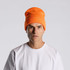 An orange beanie worn by a model, featuring a fitted design and a casual style.