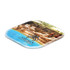 A square coaster featuring a scenic image of a resort with lounge chairs, in vibrant blue and natural tones.
