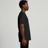 A black recycled t-shirt displayed on a model from the side, featuring a simple design and a logo.