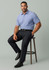 A men's adjustable waist straight leg pant in navy, styled with a blue shirt, seated on a stool.