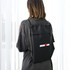 A black drawstring bag with a logo, worn on the back of a person, featuring a sleek design.