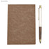 A brown notebook with a textured cover and a white pen with a wooden design, featuring a logo.