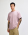 A model wearing a purple American Apparel Super Heavyweight T-Shirt, featuring short sleeves and a relaxed fit.