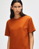 An orange American Apparel Super Heavyweight T-Shirt on a model, featuring a round neckline and short sleeves.