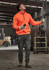 A unisex water-resistant 1/4 zip pullover in bright orange, worn with dark grey trousers, set in an industrial environment.