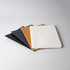 A set of four notebooks in black, navy, brown, and white, featuring smooth covers and a clean design.