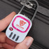 A hand holds a pink and white TSA lock with a logo, designed for securing luggage.