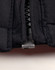 A close-up of a black heavy quilted jacket, highlighting the zip and stitching details. The jacket features a logo.