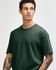 A heavyweight cotton unisex t-shirt in dark green, worn by a model with curly hair. Features a simple, classic design.